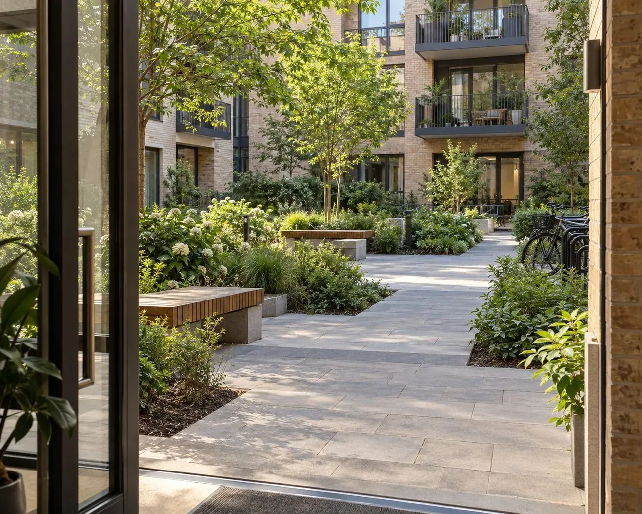 Landscaped courtyard of a managed residential building with benches and bicycle parking